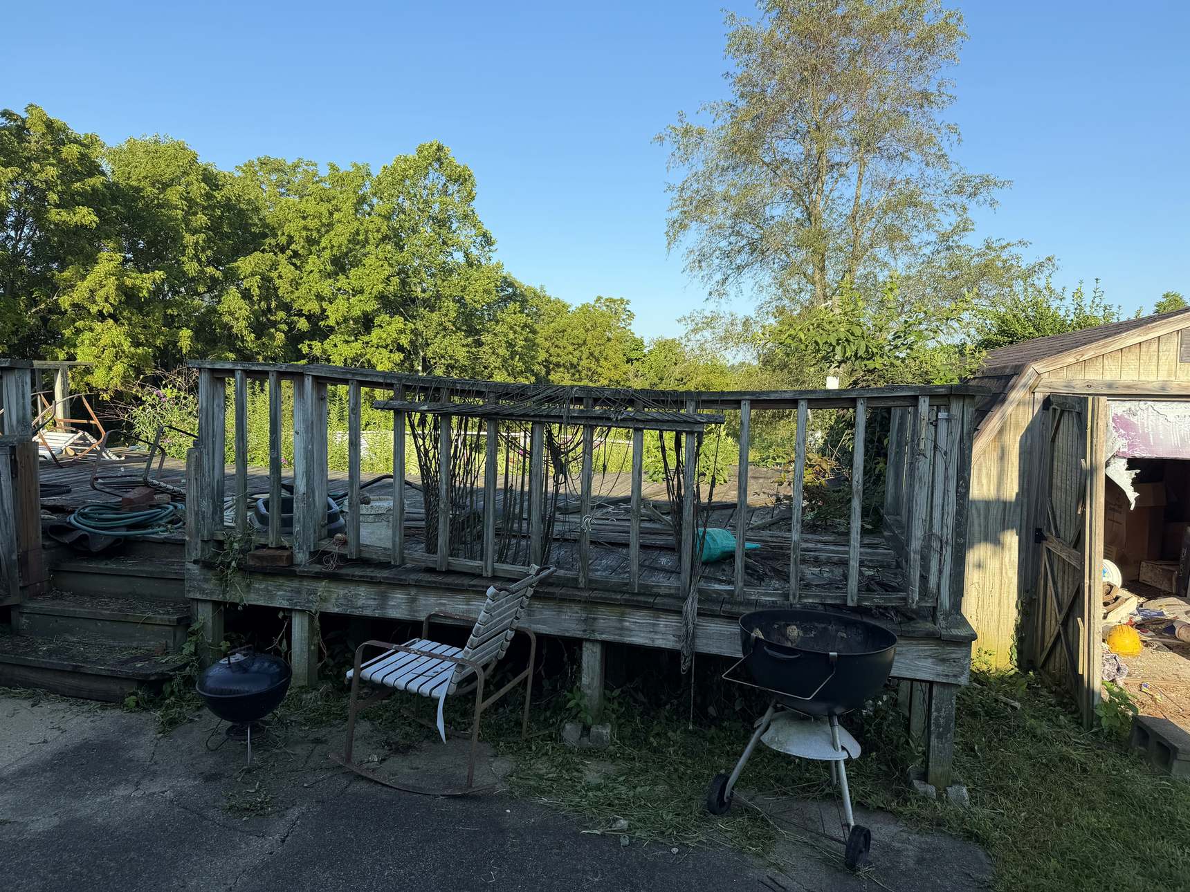 A weathered raised wooden deck with chairs and grills, before removal